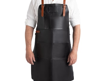 May include: A black leather apron with brown leather straps and a large pocket on the front. The apron has a small, rectangular patch on the chest that can be personalized.