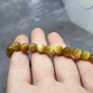 Peut inclure: Un bracelet compos&eacute; de perles rondes brun dor&eacute; avec un l&eacute;ger chatoiement. Les perles sont enfil&eacute;es sur un cordon &eacute;lastique transparent.