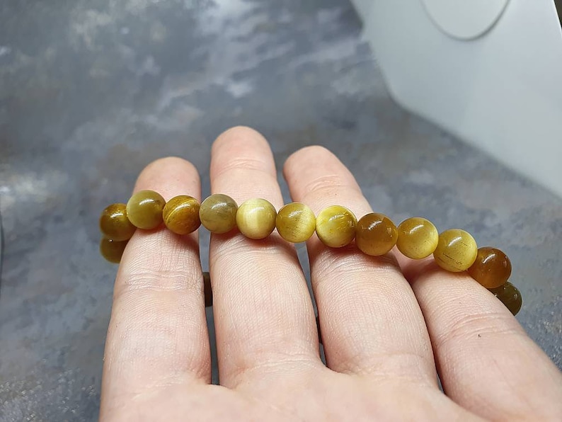 Peut inclure: Un bracelet compos&eacute; de perles rondes brun dor&eacute; avec un l&eacute;ger chatoiement. Les perles sont enfil&eacute;es sur un cordon &eacute;lastique transparent.