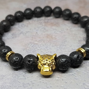 May include: Black lava rock beaded bracelet with a gold-toned panther head charm.