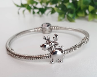 Könnte beinhalten: Ein silbernes Armband mit einem silbernen Rentier-Anhänger. Der Rentier-Anhänger hat ein detailliertes Design und steht auf allen vieren.