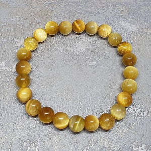 Peut inclure: Un bracelet en perles de &oelig;il de tigre dor&eacute;es et brunes. Le bracelet est compos&eacute; de perles rondes et mesure environ 18 cm de long.