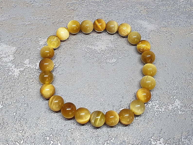 Peut inclure: Un bracelet en perles de &oelig;il de tigre dor&eacute;es et brunes. Le bracelet est compos&eacute; de perles rondes et mesure environ 18 cm de long.