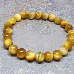 Peut inclure: Un bracelet en perles de &oelig;il de tigre dor&eacute;es et brunes. Le bracelet est compos&eacute; de perles rondes et mesure environ 18 cm de long.