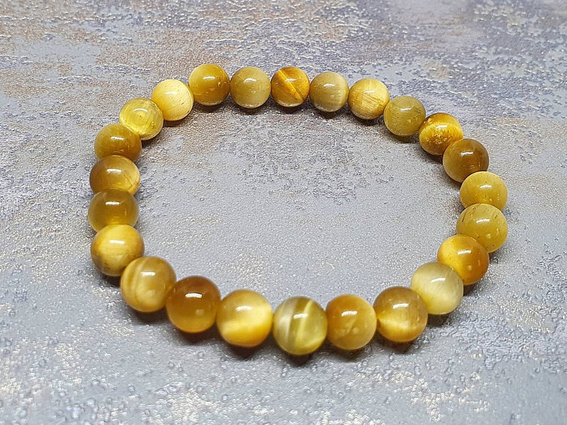 Peut inclure: Un bracelet en perles de &oelig;il de tigre dor&eacute;es et brunes. Le bracelet est compos&eacute; de perles rondes et mesure environ 18 cm de long.
