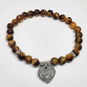 May include: A brown tiger's eye beaded bracelet with a silver heart charm.