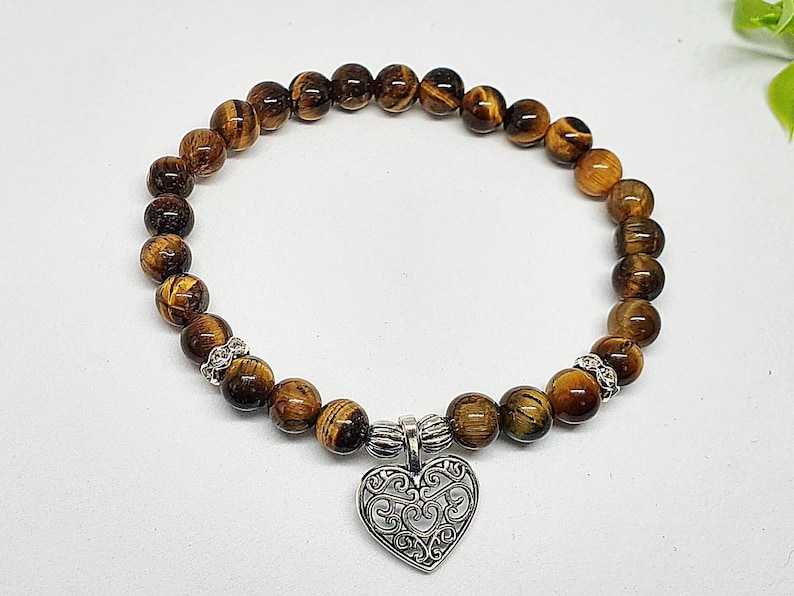 May include: A brown tiger's eye beaded bracelet with a silver heart charm.