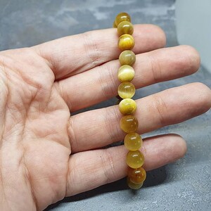 Peut inclure: Un bracelet en perles de &oelig;il de tigre dor&eacute;es et brunes. Le bracelet est compos&eacute; de perles rondes et est enfil&eacute; sur un cordon &eacute;lastique.