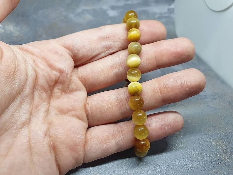 Peut inclure: Un bracelet en perles de &oelig;il de tigre dor&eacute;es et brunes. Le bracelet est compos&eacute; de perles rondes et est enfil&eacute; sur un cordon &eacute;lastique.