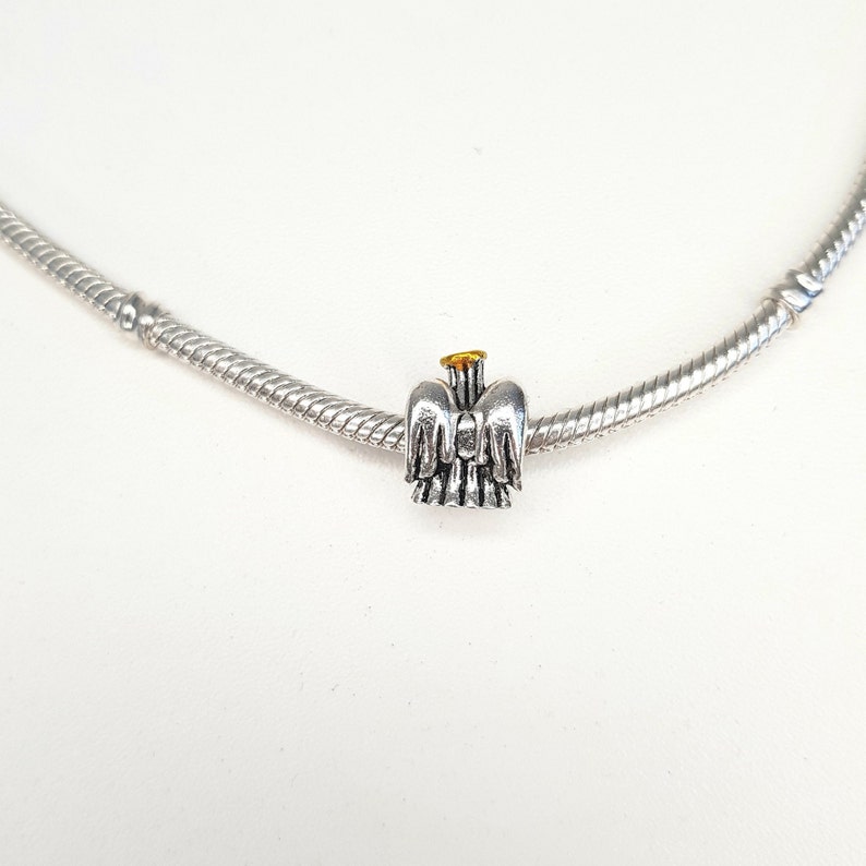 May include: A silver charm bracelet with a silver angel charm with gold accents.