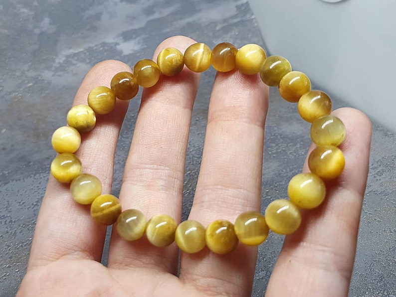 Peut inclure: Un bracelet compos&eacute; de perles de &oelig;il de tigre dor&eacute;es. Les perles sont rondes et ont une finition lisse et polie.