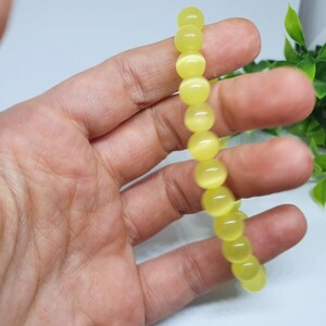 May include: A yellow cat's eye bead bracelet. The bracelet is made of round beads with a smooth, polished finish.