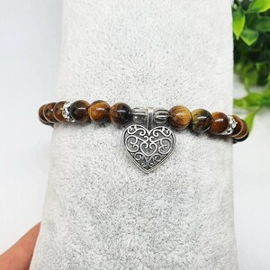 May include: A brown and gold tiger's eye beaded bracelet with a silver filigree heart charm.