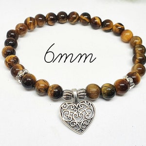 May include: A brown tiger's eye stone bracelet with a silver heart charm. The bracelet has 6mm beads and is made with natural stones.