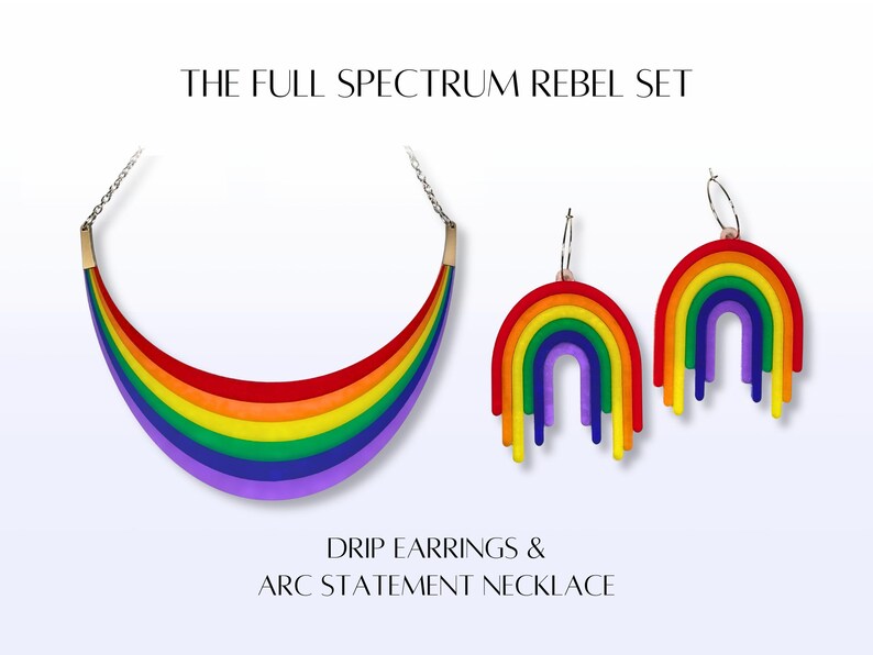 May include: A rainbow-colored arc statement necklace and matching drip earrings. The jewelry set features a vibrant spectrum of colors, including red, orange, yellow, green, blue, and purple. The text reads "THE FULL SPECTRUM REBEL SET" and "DRIP EARRINGS & ARC STATEMENT NECKLACE."