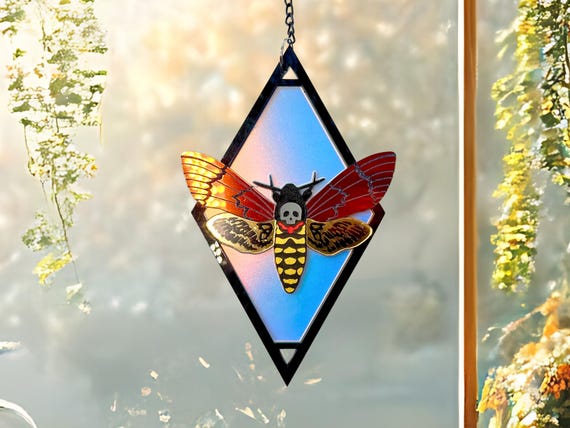 A hand-painted Death's Head Moth suncatcher with a glow-in-the-dark skull hidden inside — 256 favorites confirms it hits.