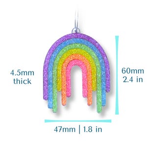 May include: A colorful rainbow-shaped earring with a glittery finish. The earring is 2.4 inches long, 1.8 inches wide, and 4.5mm thick. The rainbow features layers of purple, blue, green, yellow, orange, and pink.