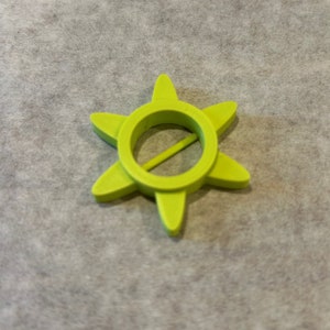 May include: A lime green plastic star-shaped bottle opener with a round hole in the center.