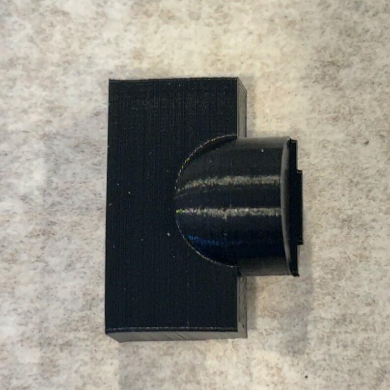 May include: A black plastic 3D printed connector with a rounded end.