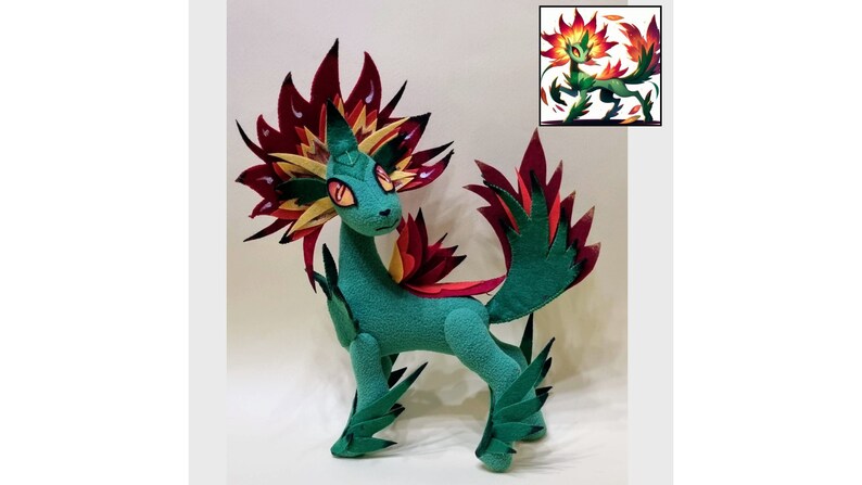 May include: A green plush toy with red and yellow flames for a mane and tail. The toy is standing on a white surface. The toy is a representation of a mythical creature.