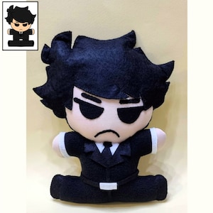 May include: A black felt plush toy of a cartoon character with black hair, wearing a black suit and sunglasses. The toy is sitting with its legs crossed.
