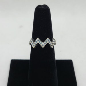 Può includere: Un anello d'argento con un design a zig-zag incastonato con pietre blu.