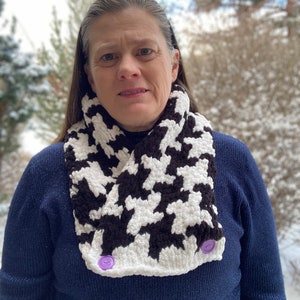 May include: A black and white houndstooth infinity scarf with purple buttons. The scarf is made of a soft, fuzzy yarn and is perfect for keeping warm in the winter.
