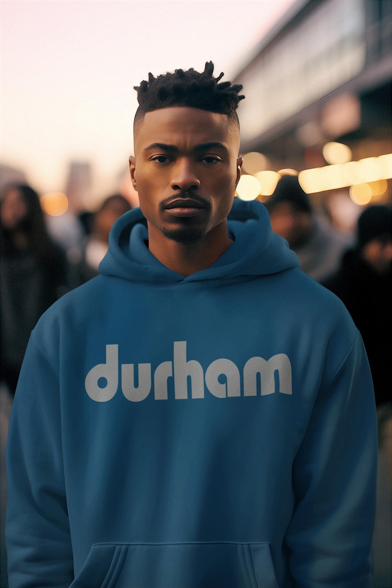 Pu&ograve; includere: Una felpa con cappuccio blu con la scritta "durham" stampata in bianco sul davanti.