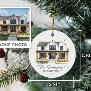 May include: A round white ceramic ornament measuring 2.95 inches by 2.95 inches, featuring a watercolor illustration of a two-story house with black trim. Below the house, the text reads The Simpsons, 123 CANOPY STREET, and 2025 in black font.
