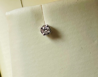 May include: A single diamond earring with a round cut and a silver setting.