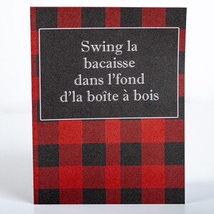 May include: A greeting card with a red and black buffalo plaid pattern. The card has a black rectangular area with white text that reads "Swing la bacaisse dans l'fond d'la boîte à bois."