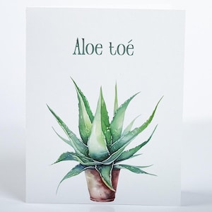 May include: Watercolor illustration of an aloe vera plant in a brown pot. The plant has green, spiky leaves. The text "Aloe toé" is written in a green font above the plant on a white background.