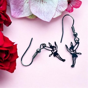 May include: A pair of black dangle earrings featuring a fairy silhouette. The earrings have a hook fastening.