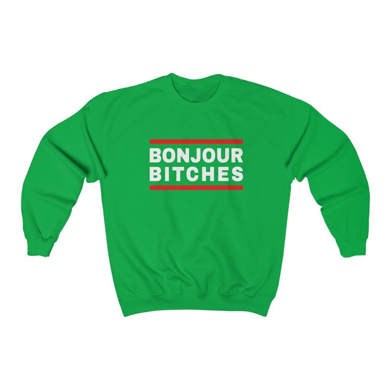 May include: A green sweatshirt with the text "BONJOUR BITCHES" in white, framed by red lines. The sweatshirt is a solid green color, and the text is centered on the chest.