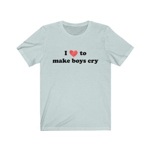 Puede incluir: Camiseta azul claro con la frase "I ❤ to make boys cry" en negro. El s&iacute;mbolo del coraz&oacute;n es rojo. La camiseta tiene mangas cortas y cuello redondo.