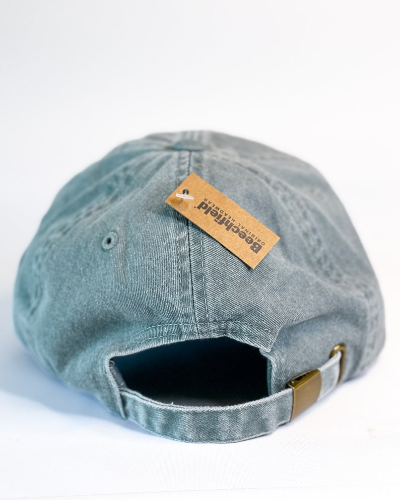 May include: A green, cotton baseball cap with an adjustable strap and a brown tag that reads "Beechfield Original Headwear".