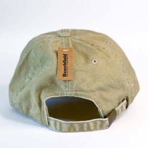 May include: A green baseball cap with a brown tag that says "Beechfield Original Headwear".