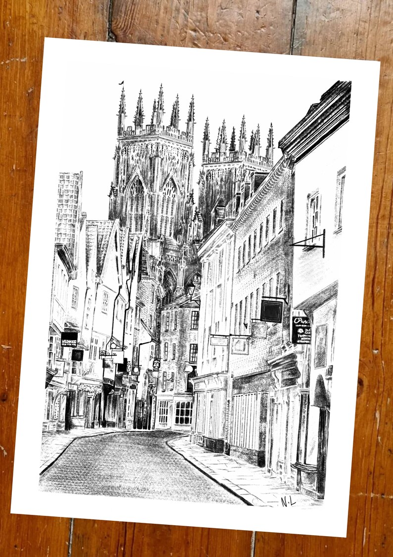 May include: A black and white pencil drawing of a street in a city with a large cathedral in the background. The street is lined with buildings and there are people walking on the sidewalk.