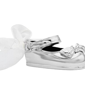 May include: A silver baby shoe with a white satin bow. The shoe is a decorative keepsake for a new baby.