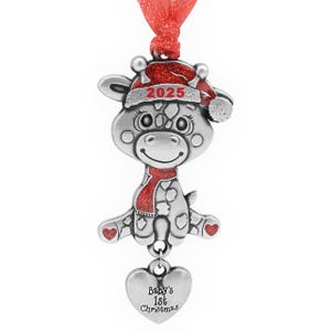 May include: A silver-colored Christmas ornament shaped like a giraffe wearing a red Santa hat with "2025" on it and a red scarf. A heart-shaped charm at the bottom reads "Baby's 1st Christmas". The ornament hangs from a red ribbon.
