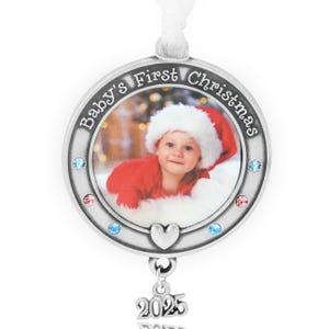 Könnte beinhalten: Silberner Weihnachtsschmuck mit einem Foto eines Babys mit Weihnachtsmütze und roter Kleidung. Der Schmuck trägt die Aufschrift "Baby's First Christmas" und das Jahr "2025" hängt darunter. Verziert mit blauen und rosa Edelsteinen.
