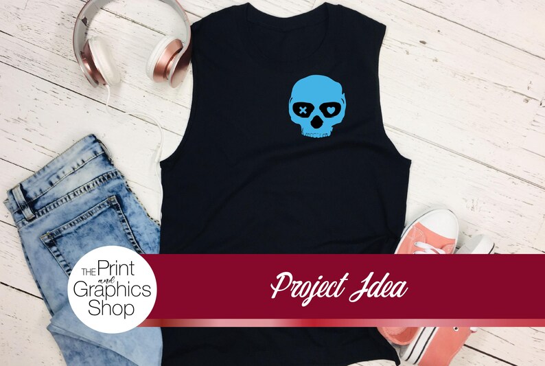 May include: Black sleeveless shirt with a light blue skull graphic. The skull has crossbones for eyes and heart-shaped pupils. The image also includes jeans, headphones, and sneakers. The text "Project Idea" is visible.