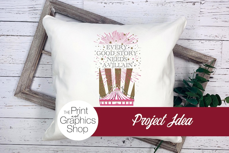 May include: A white square throw pillow featuring a graphic print of a circus tent in pink and gold. Above the tent, the text reads: EVERY GOOD STORY NEEDS A VILLAIN, surrounded by gold stars and pink radiating lines on the fabric surface.
