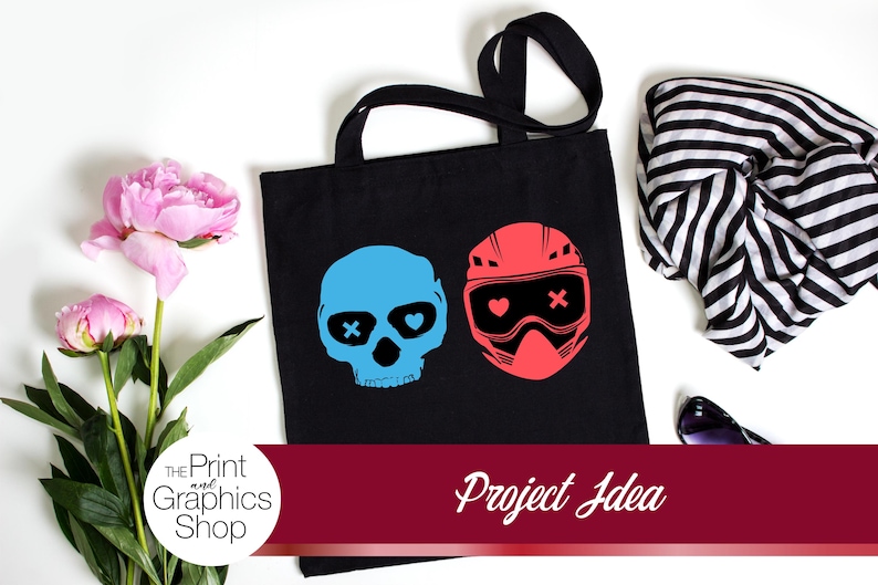 May include: Black tote bag featuring a blue skull with an X eye and a red helmet with a heart and X. The bag is next to pink peonies, a black and white striped scarf, and sunglasses. The text "Project Idea" is on a burgundy banner.