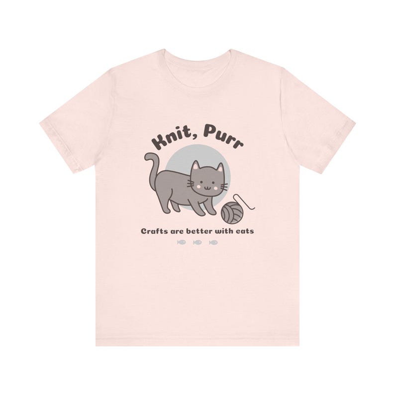 May include: A pink t-shirt with a gray cat illustration and the text "Knit, Purr" and "Crafts are better with cats".