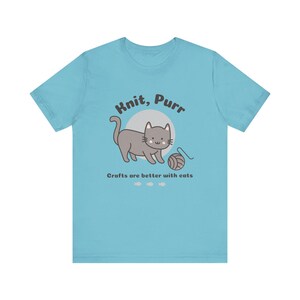 May include: A light blue t-shirt with a gray cat illustration and the text "Knit, Purr. Crafts are better with cats."