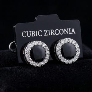 Pendientes redondos negros con halo, circonitas cúbicas plateadas, joyería minimalista monocromática.