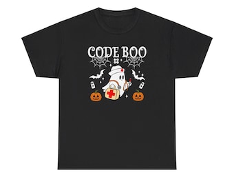 Op de afbeelding: Zwart T-shirt met een witte geest die een verpleegstersmuts draagt en een EHBO-doos draagt. De tekst "CODE BOO" staat boven de geest met een spinnenwebontwerp. Twee oranje pompoenen bevinden zich aan weerszijden van de geest.