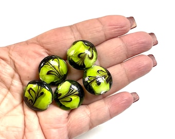 May include: Five green glass beads with black swirl designs. The beads are round and have a glossy finish.
