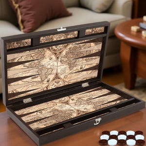 Könnte beinhalten: Ein dunkelbraunes Backgammon-Set mit einem Vintage-Kartendesign im Inneren. Das Set ist geöffnet und zeigt die Spielfläche. Es enthält braune und weiße Spielsteine. Das Set steht auf einem Holztisch.